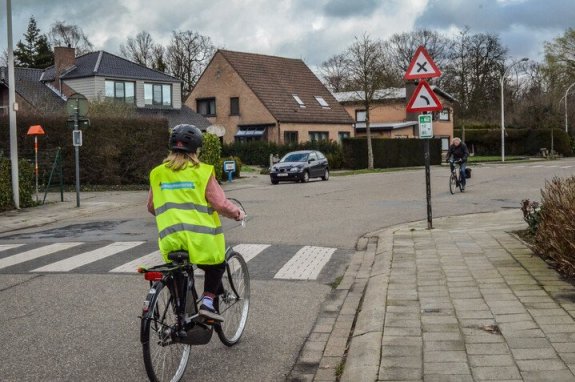 kind met de fiets aan een kruispunt met verkeersborden