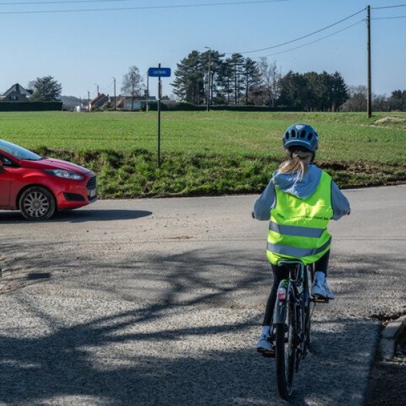 Kind met de fiets aan een kruispunt met voorrang van rechts, een auto komt van rechts
