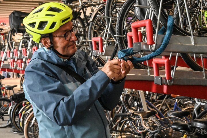 fietser die fiets op slot legt aan fiesenrek in fietsenstalling