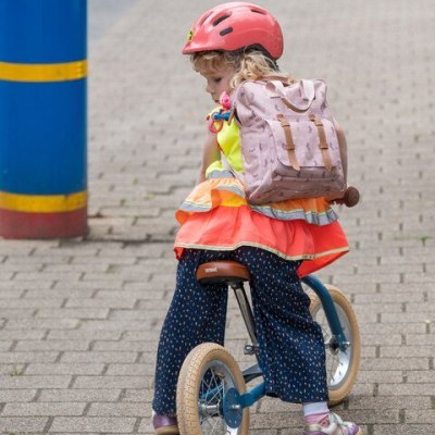kind op loopfiets met boekentas op de rug
