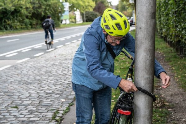 Man die fietsslot rond fiets en paal legt op een berm