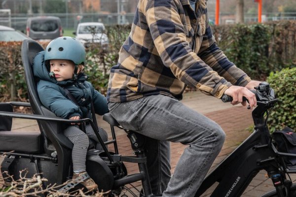 man die fietst met kind in fietsstoel op longtailfiets