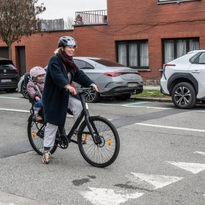 moeder fietst in het verkeer met kind achterop in fietsstoel