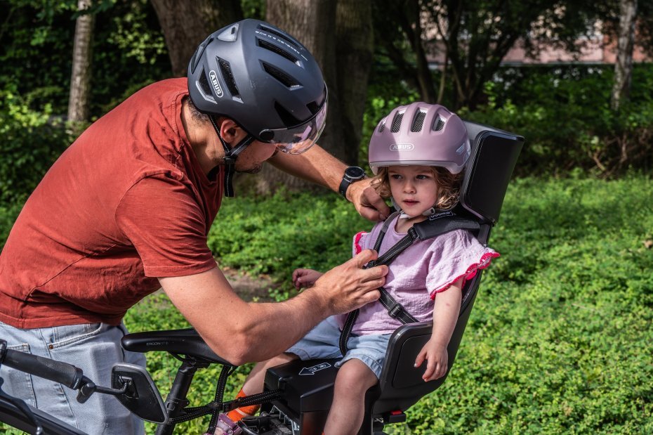 ouder die kind in fietsstoeltje zet