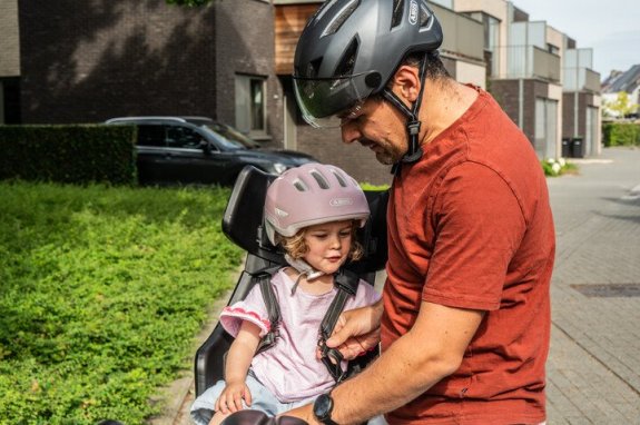 ouder die kind in fietsstoel zet