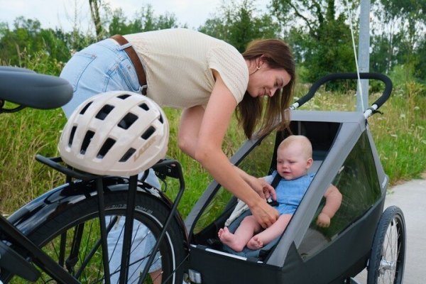 moeder die kind in fietskar zet