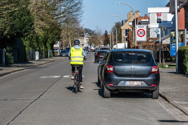 fietser die geparkeerde auto voorbij rijdt
